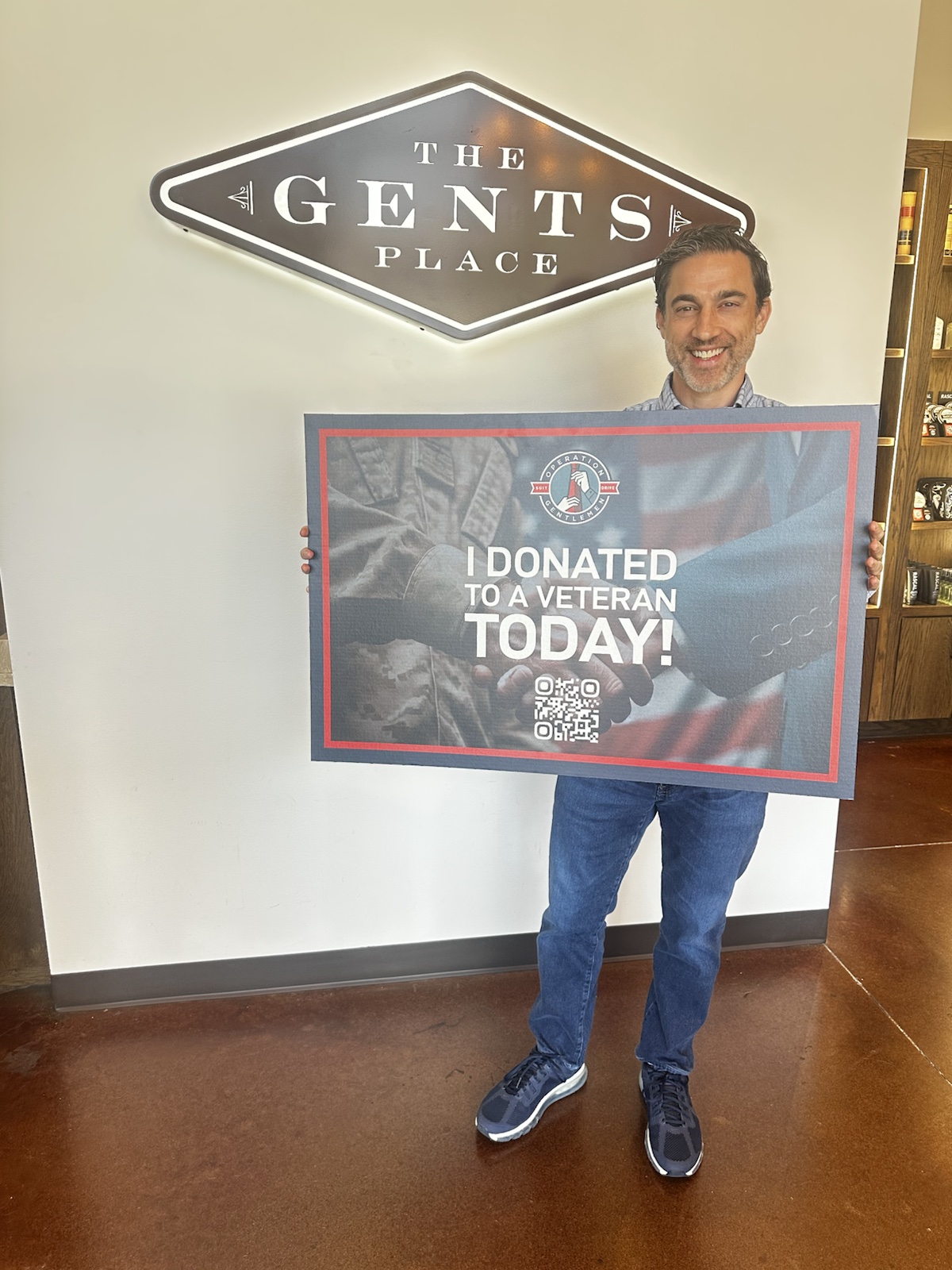 Ben Davis holding an Operation Gentlemen sign after donating to support a veteran